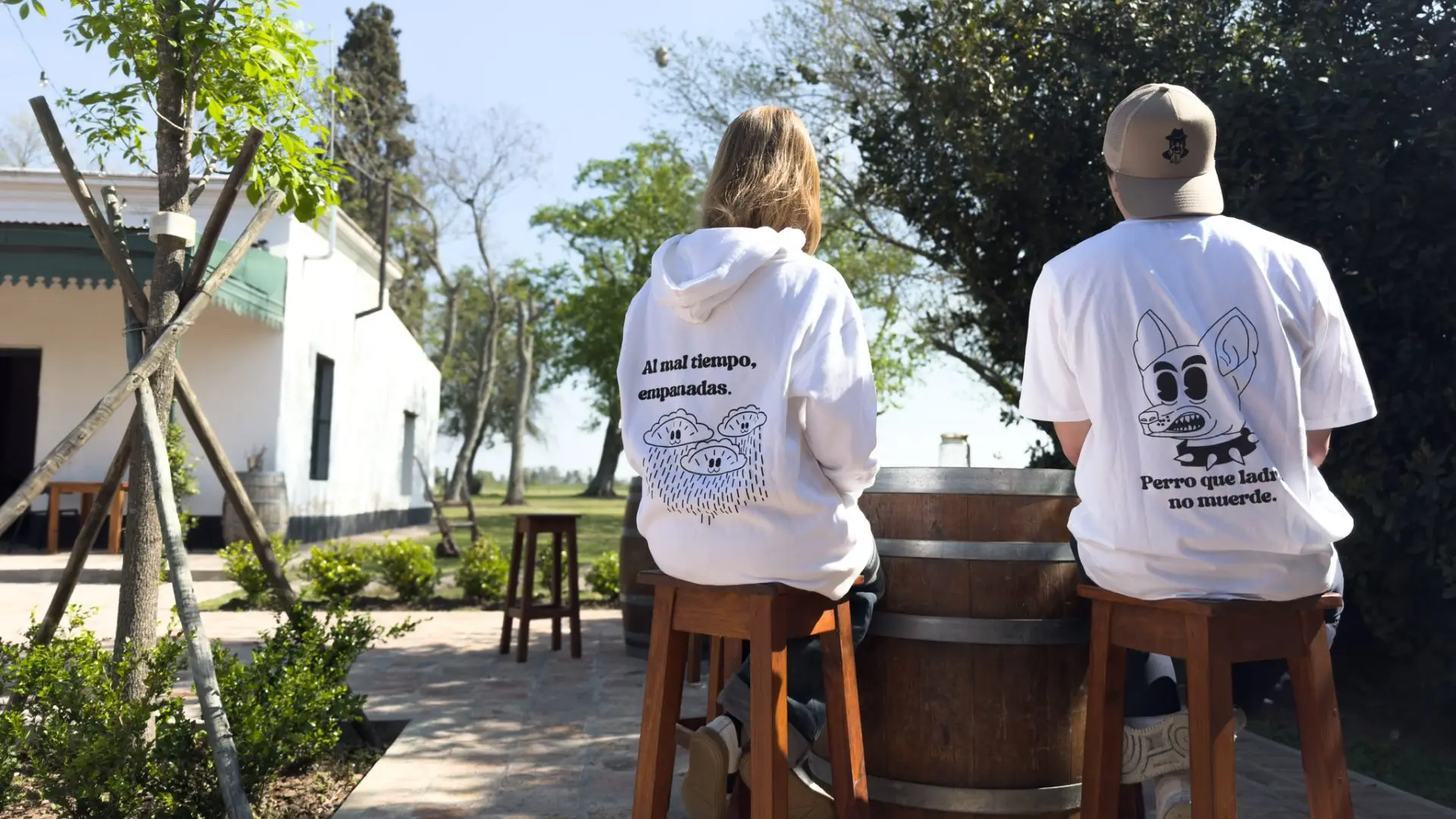 Merch de El Malevo: hoodie y remera con las ilustraciones "Al mal tiempo, empanadas" y "Perro que ladra no muerde"